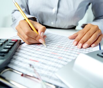 Photo of hands holding pencil and ticking data in documents